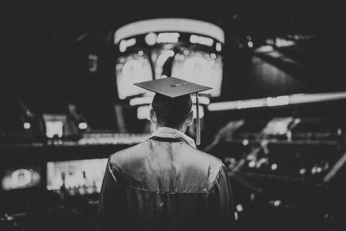 black and white photo of college student in graduation cap and gown, debating between deferred tuition vs ISA plans.