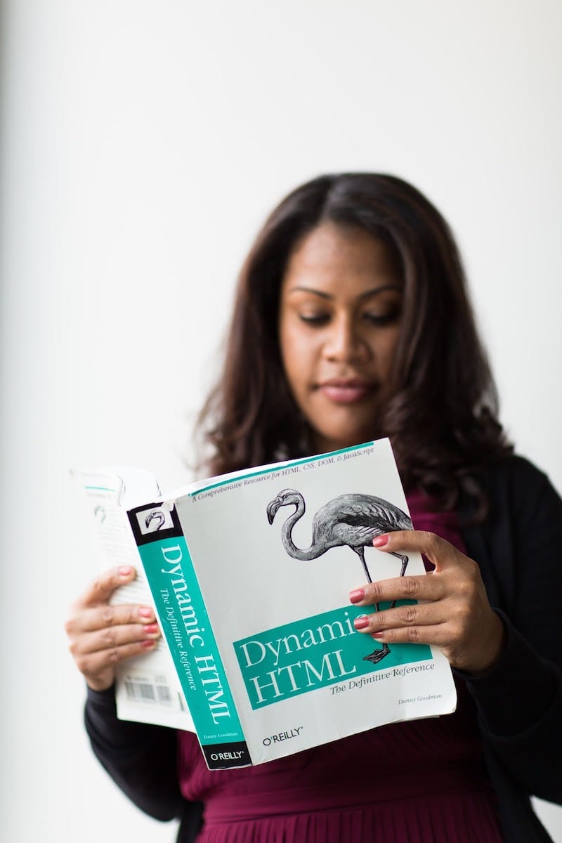 Image of woman reading Dynamic HTML textbook.