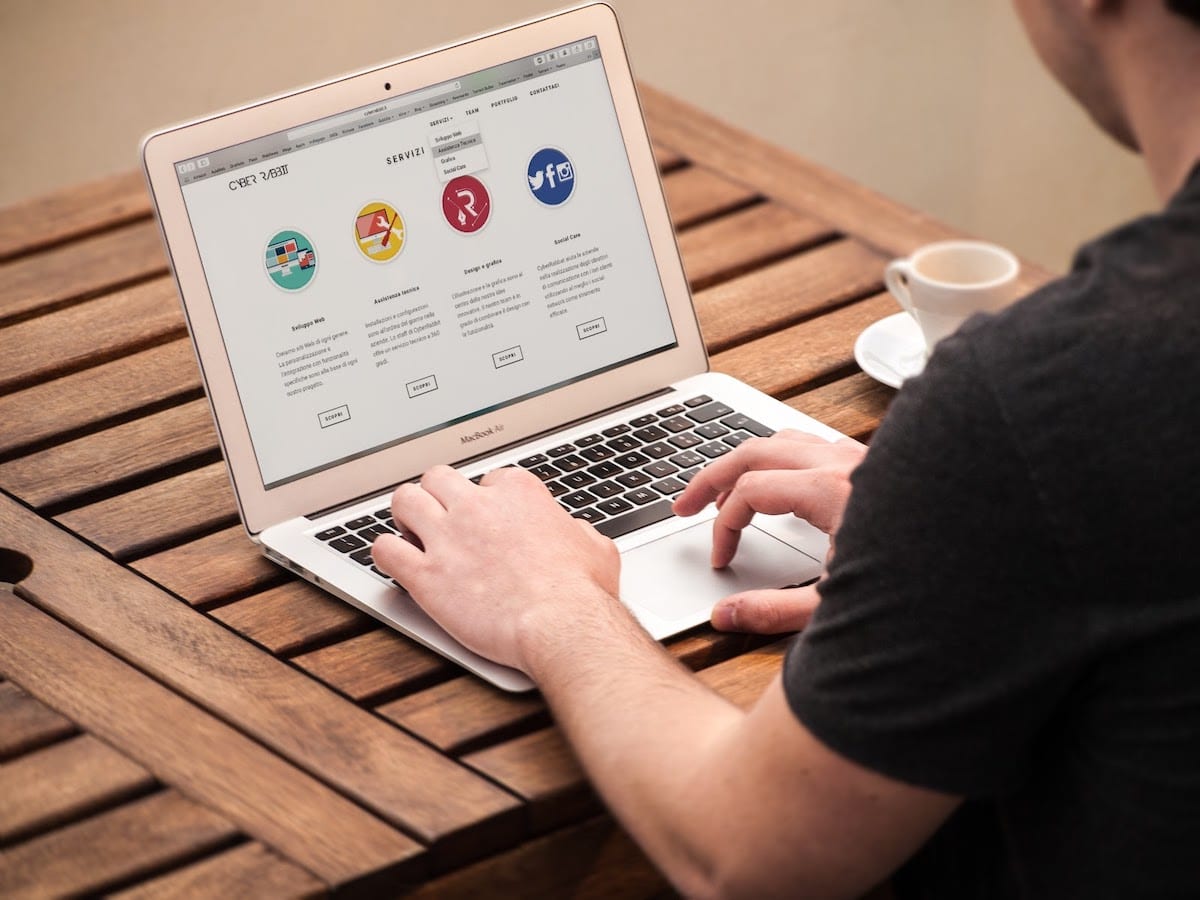 Image of a man working on a laptop with coffee.