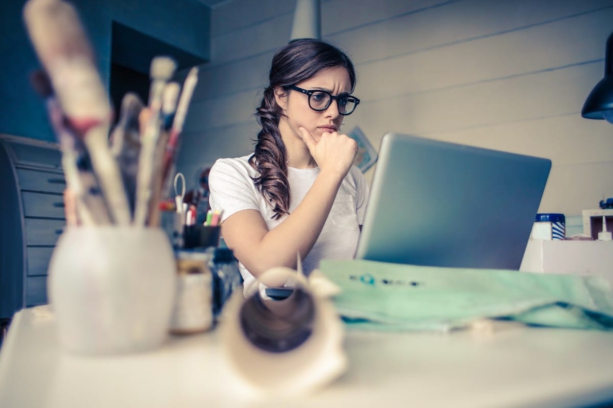 Woman studying a computer screen, wondering: is coding bootcamp worth it?