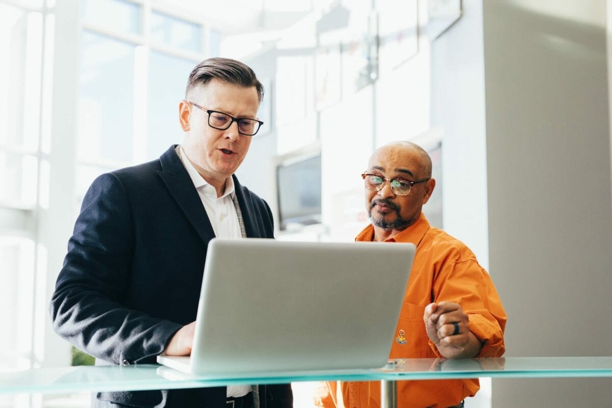  Image of men collaborating around a computer.