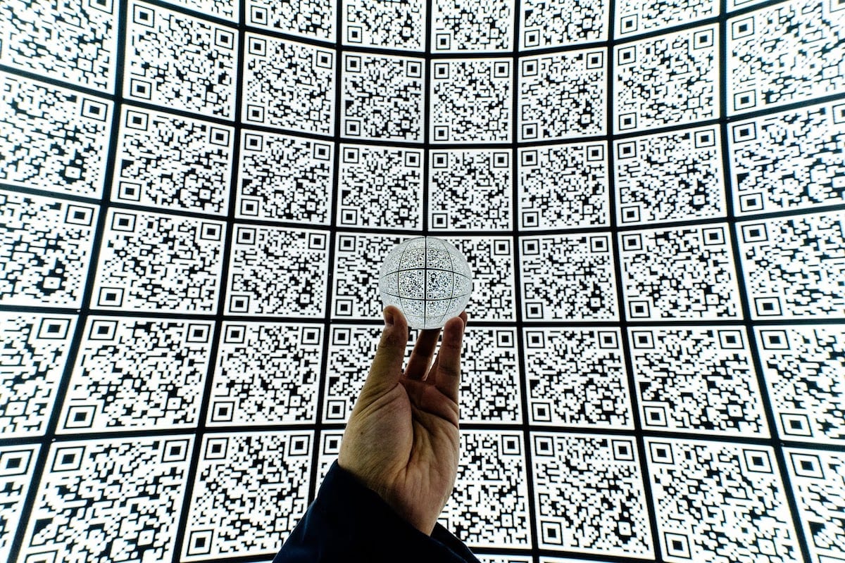 Person holding clear glass ball with QR code background”