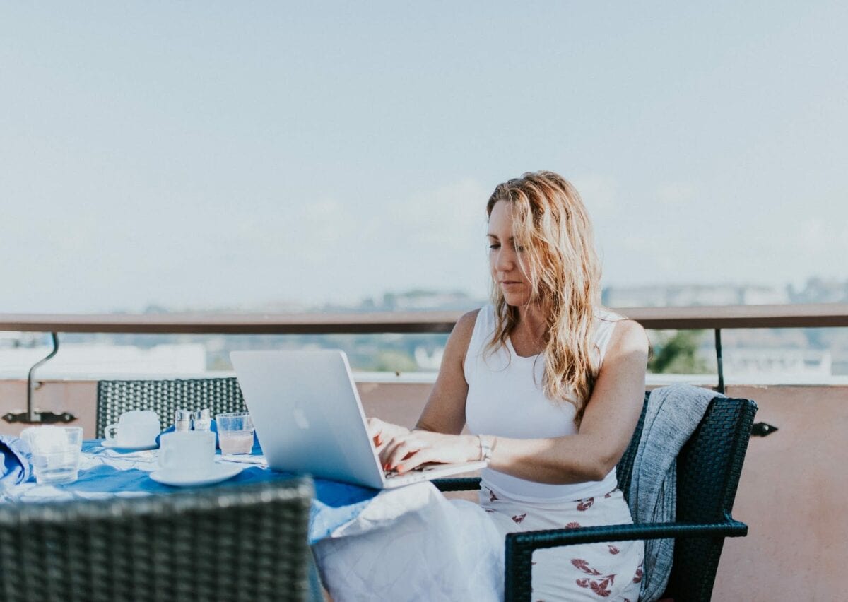 Image of woman working on a computer at a waterfront cafe.