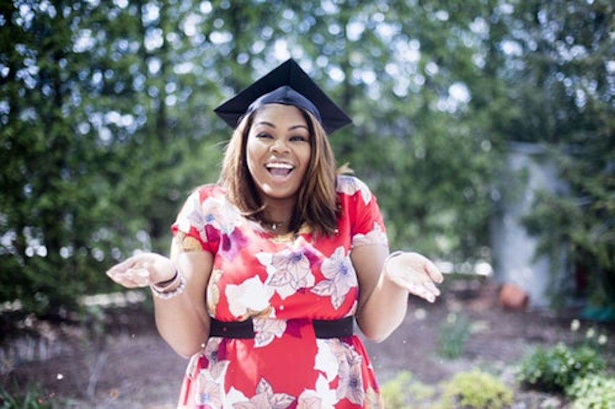 Woman wearing academic hat standing in garden showing palm at daytime”