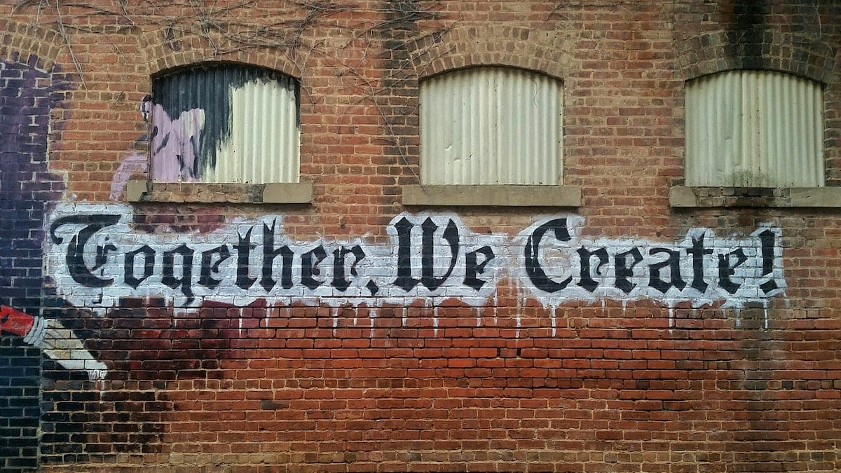 “Picture of graffiti on a brick wall that signifies teamwork.”