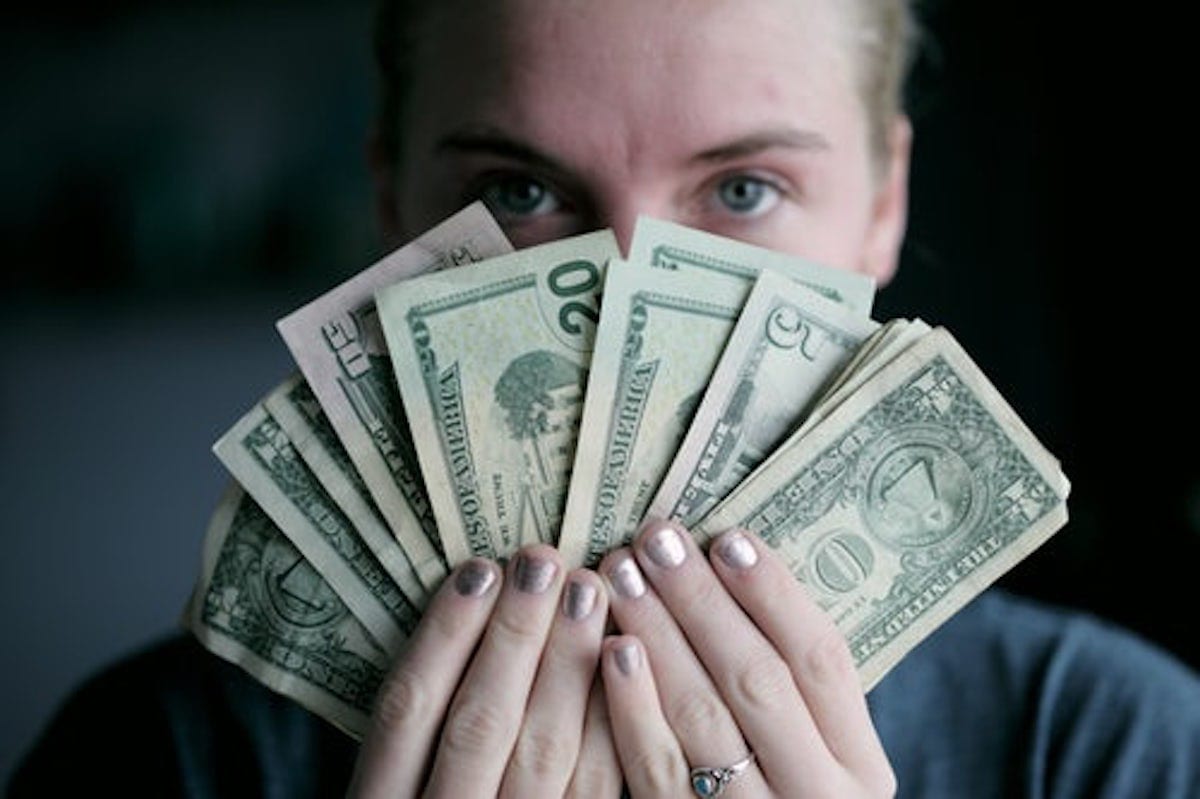 A person holding various US dollar notes
