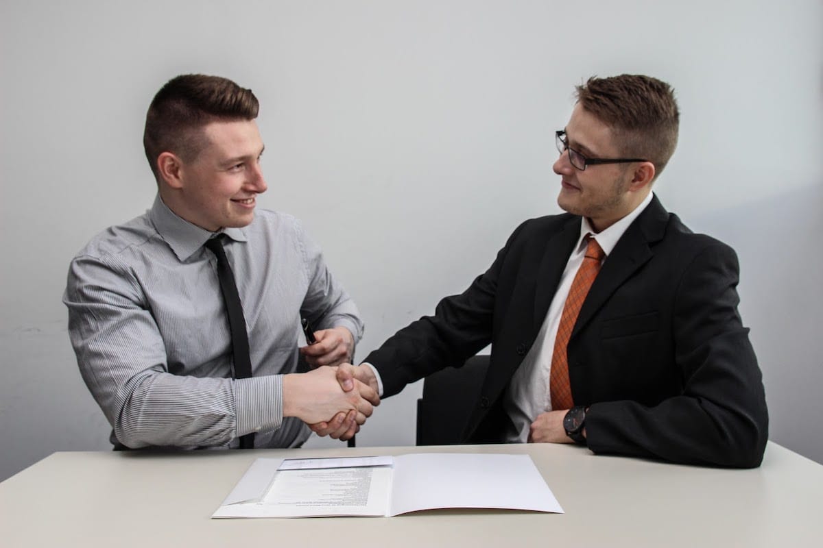 Two people in business attire shaking hands.