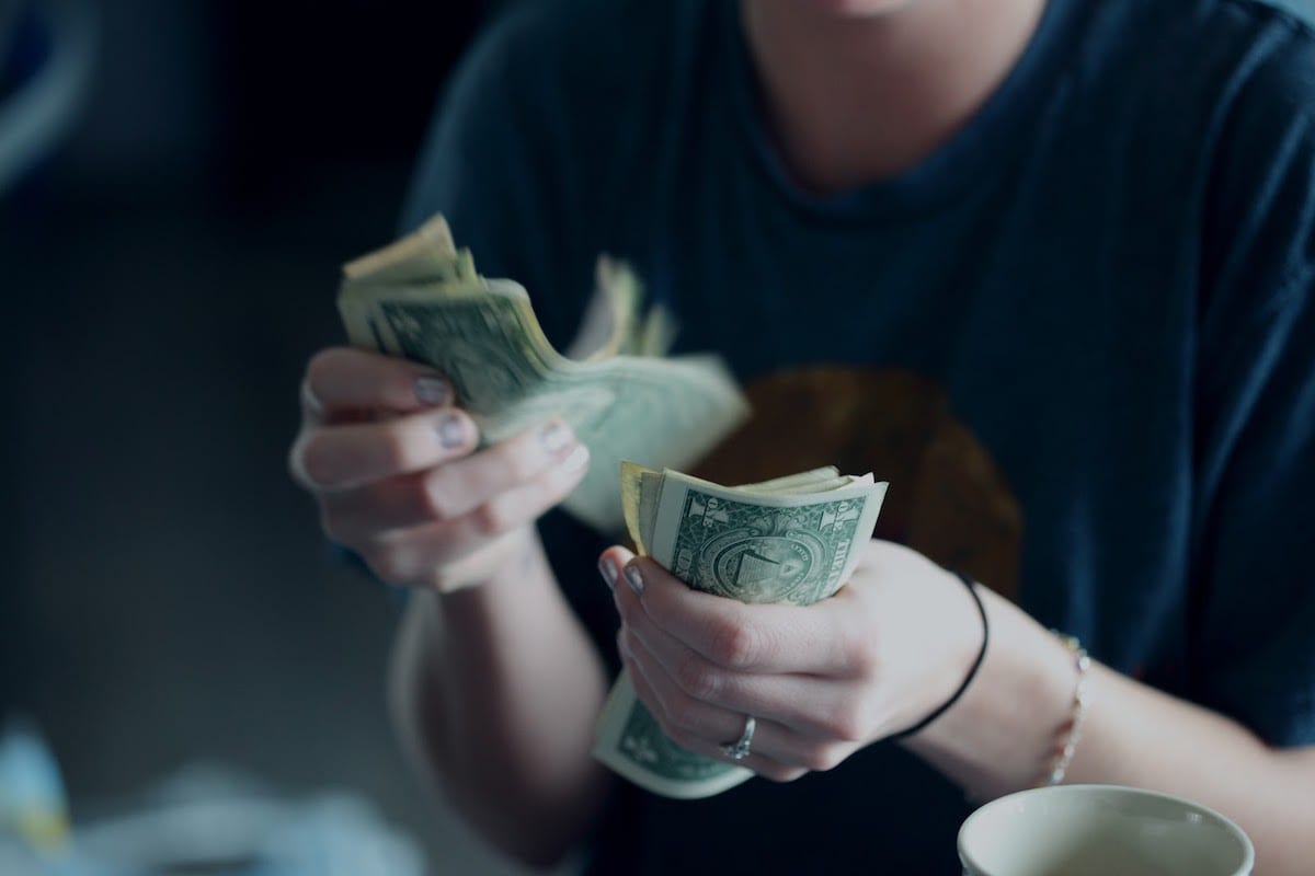 A person counting multiple notes of $1 in both hands.