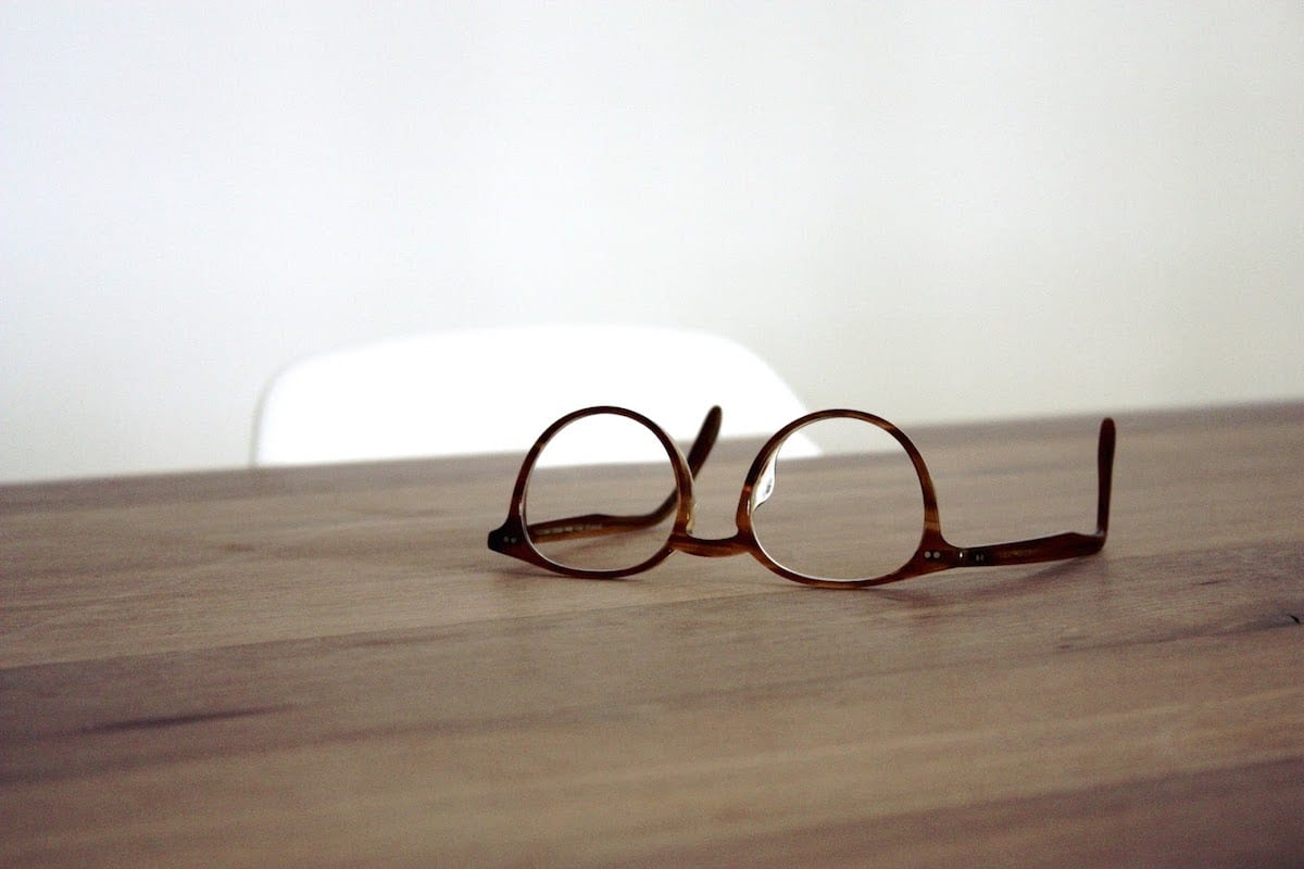 A pair of glasses sitting on top of a wooden table.
