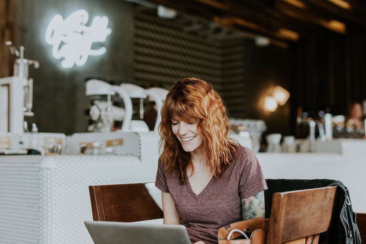 A woman sitting in a coffee shop working on a Columbia Engineering bootcamp on a computer
