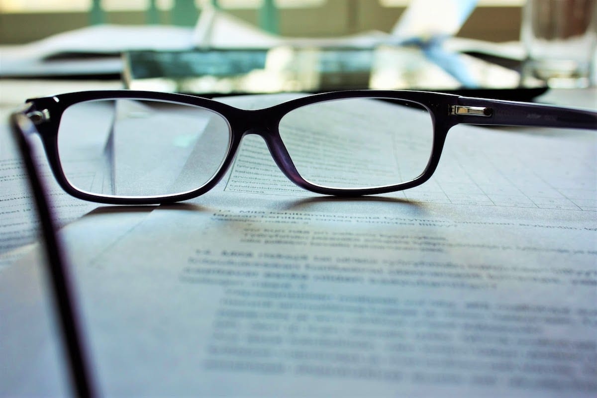 A pair of glasses sitting on a stack of papers.