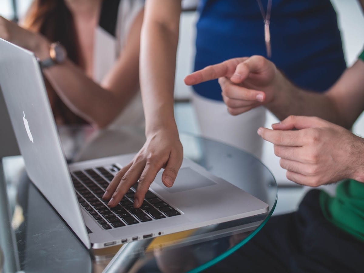  People pointing at and using laptops. 