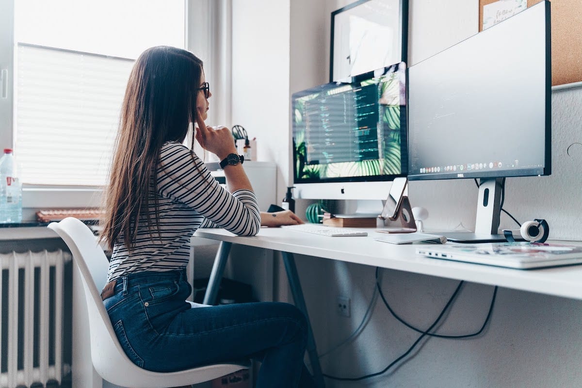 Image of a woman coding on a desktop computer.