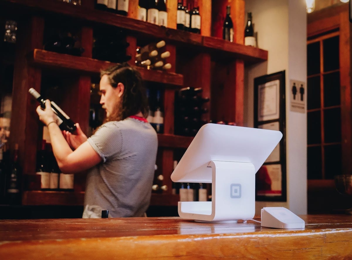 A bartender inspecting a bottle of wine.