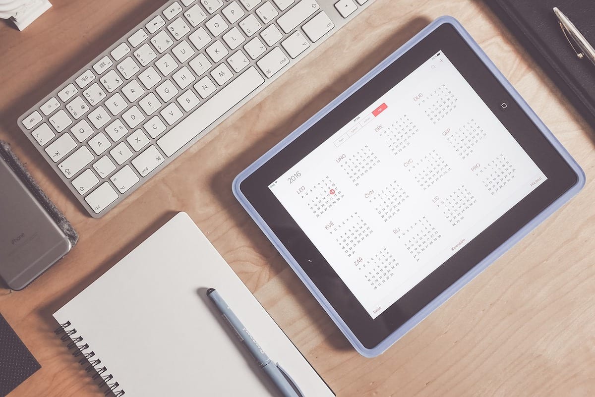 A tablet displaying a Rice University class schedule beside a blank notebook and computer keyboard.