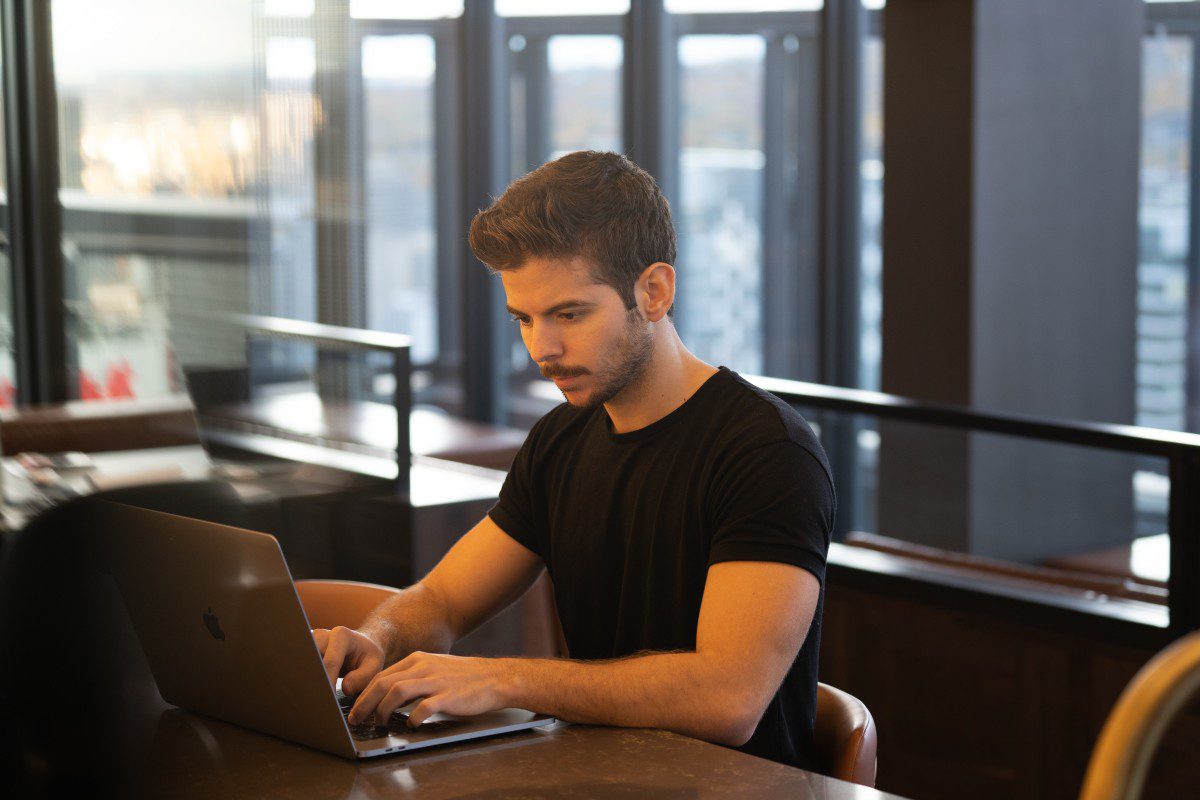 A WUSTL Coding bootcamp graduate working a new job on a laptop at a desk.