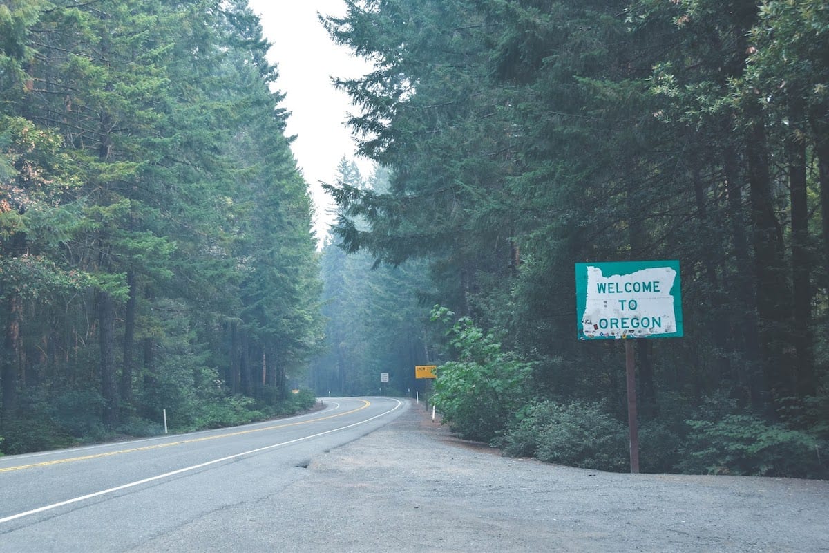 A street turn with a sign welcoming the driver to Oregon.