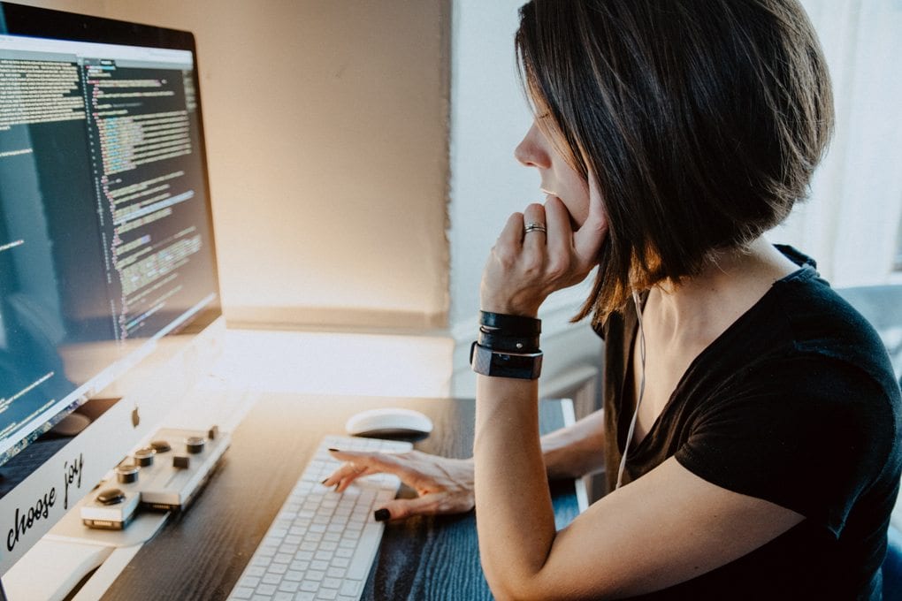 Woman wearing black shirt sitting at desk, working on computer