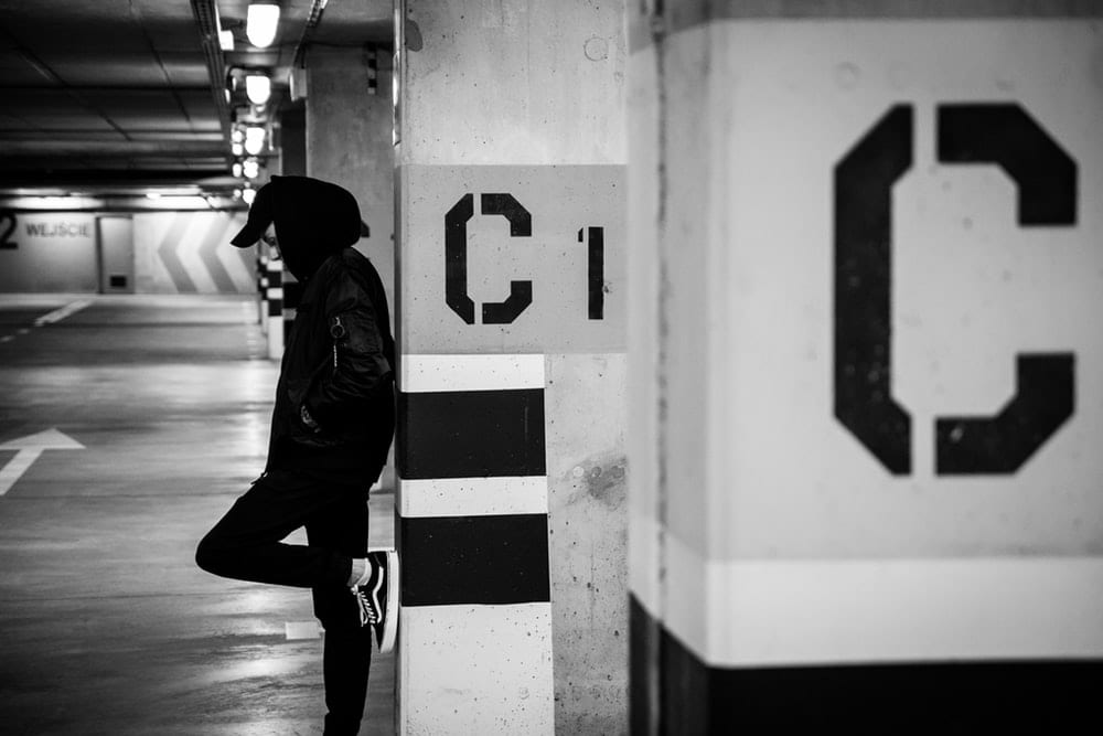 Man leaning against a column with a C on it.