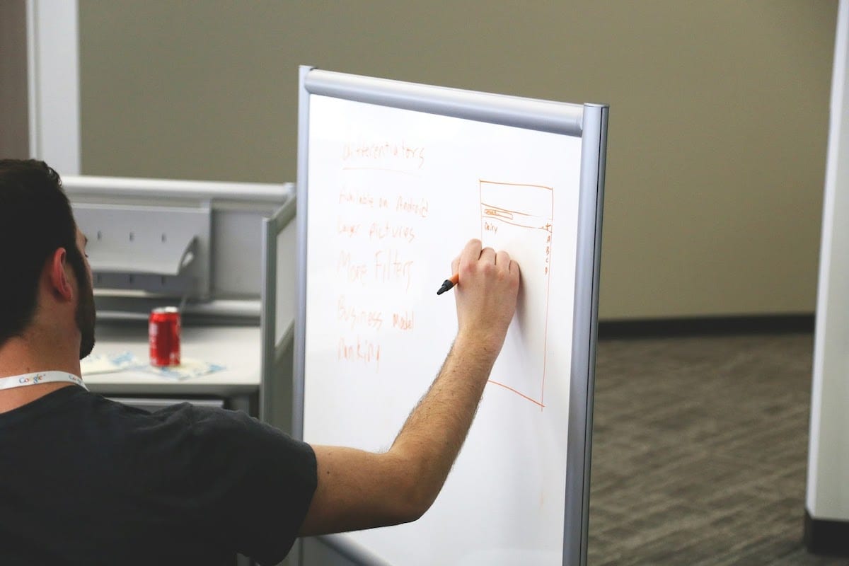 A person draws a table on a whiteboard.