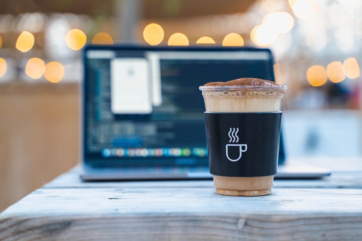 A cup of coffee in front of a laptop.