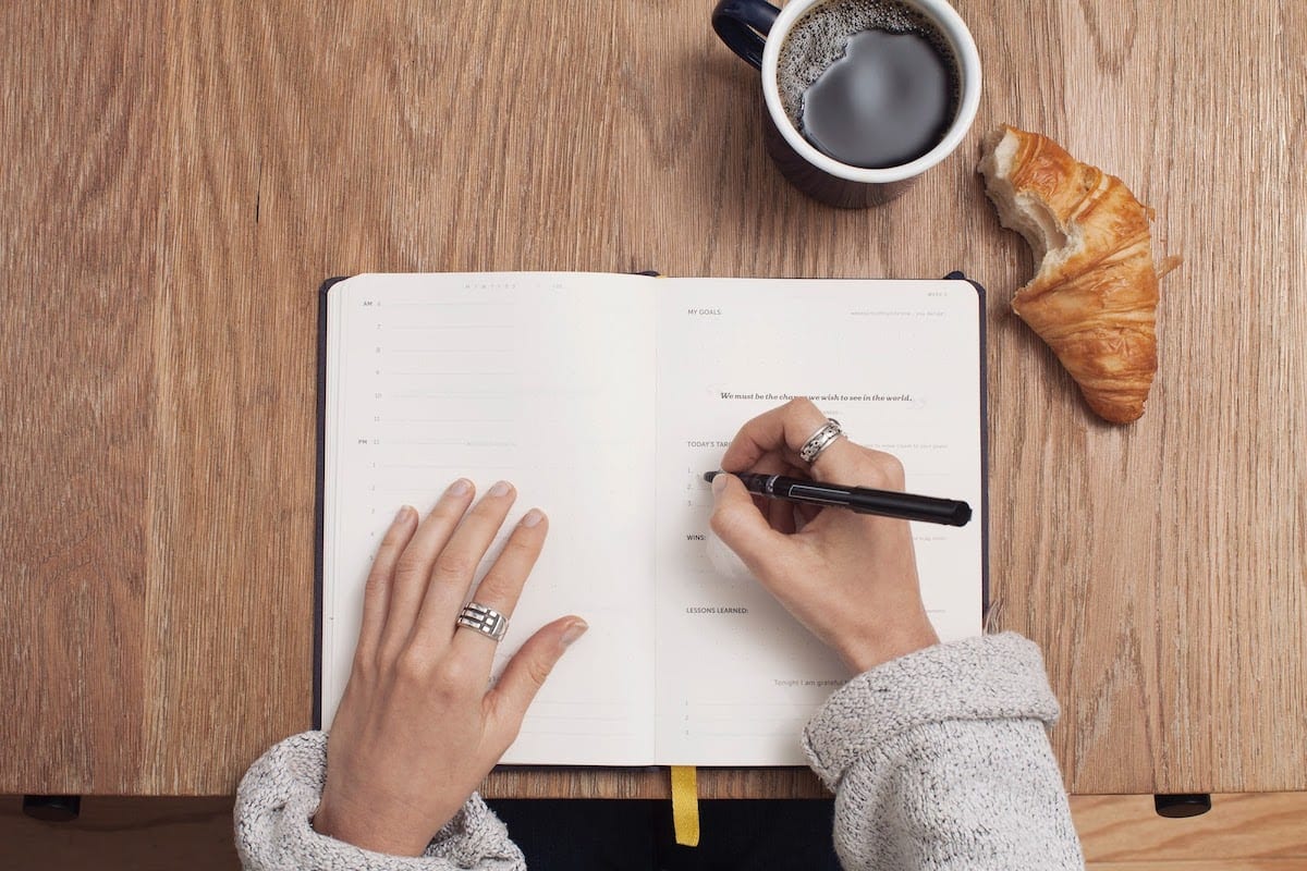 Image of a woman writing in a planner.