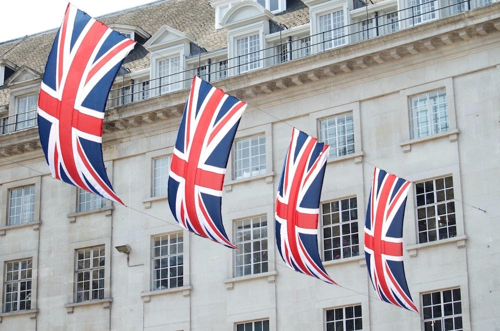 A building with multiple flags of the United Kingdom hanging from it.