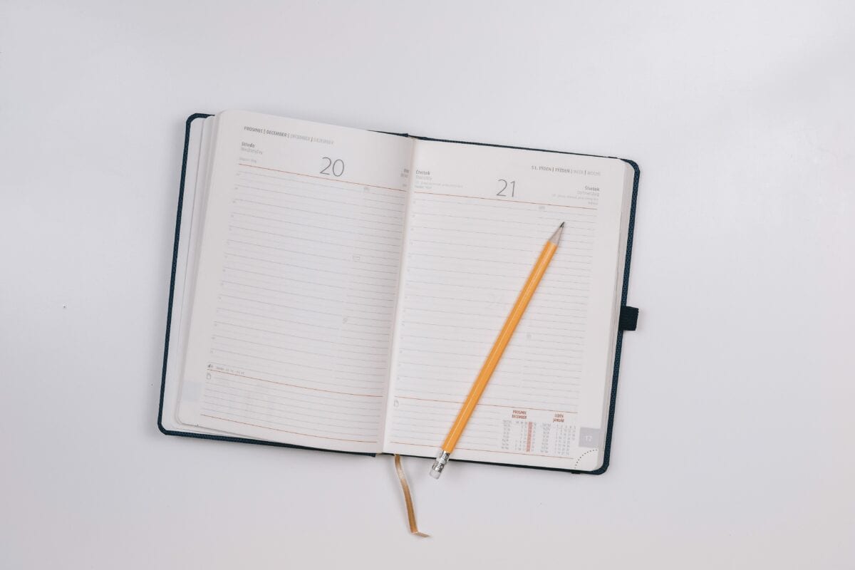 A planner lying open with a pencil on top. 