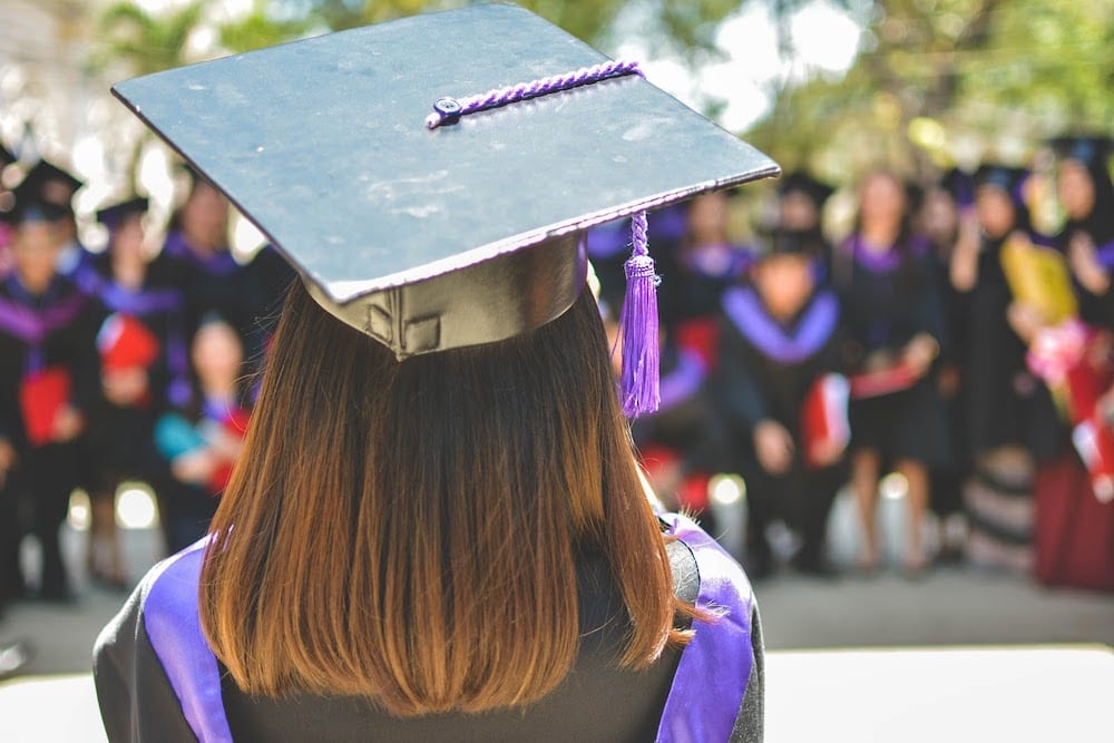 A student who received two bachelor’s degrees standing in front of their fellow graduates.
