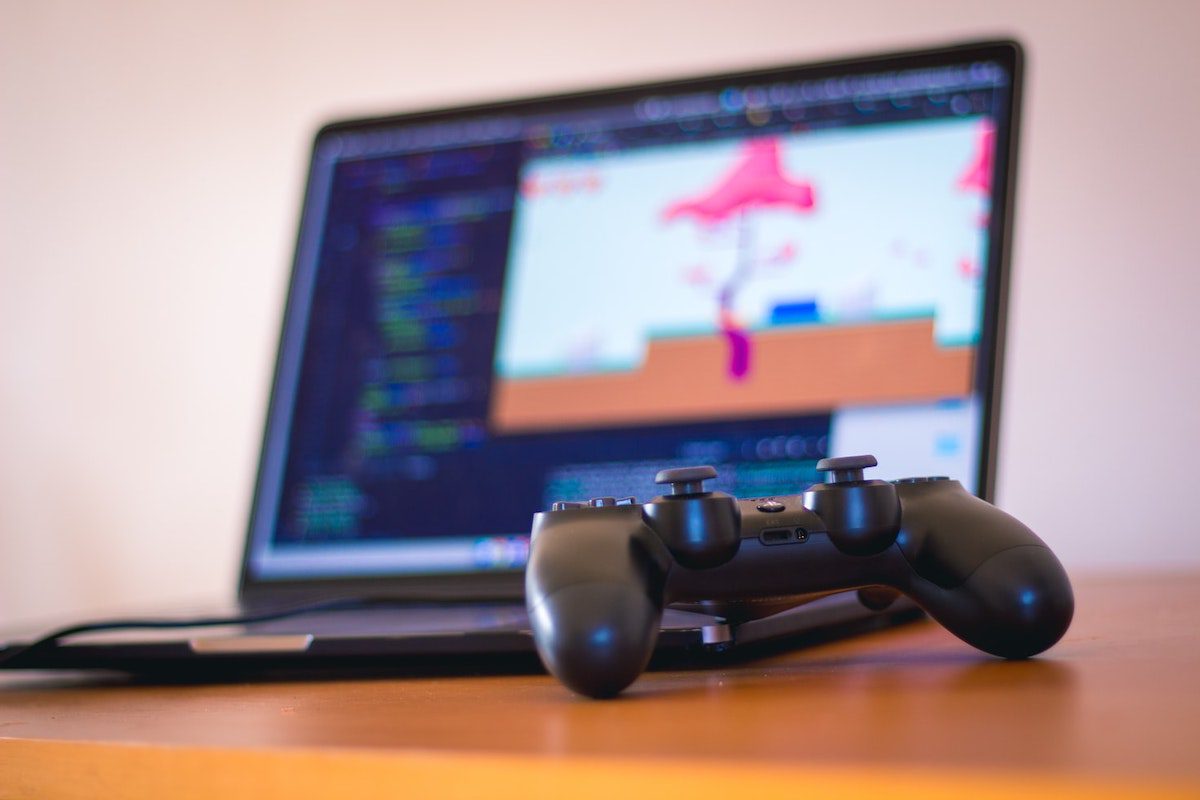  a gaming hand controller in front of a laptop with design software opened Online Game Design Courses