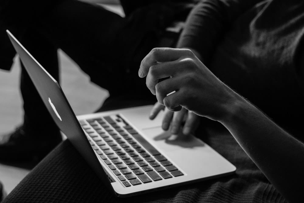 Grayscale of a person using a macbook