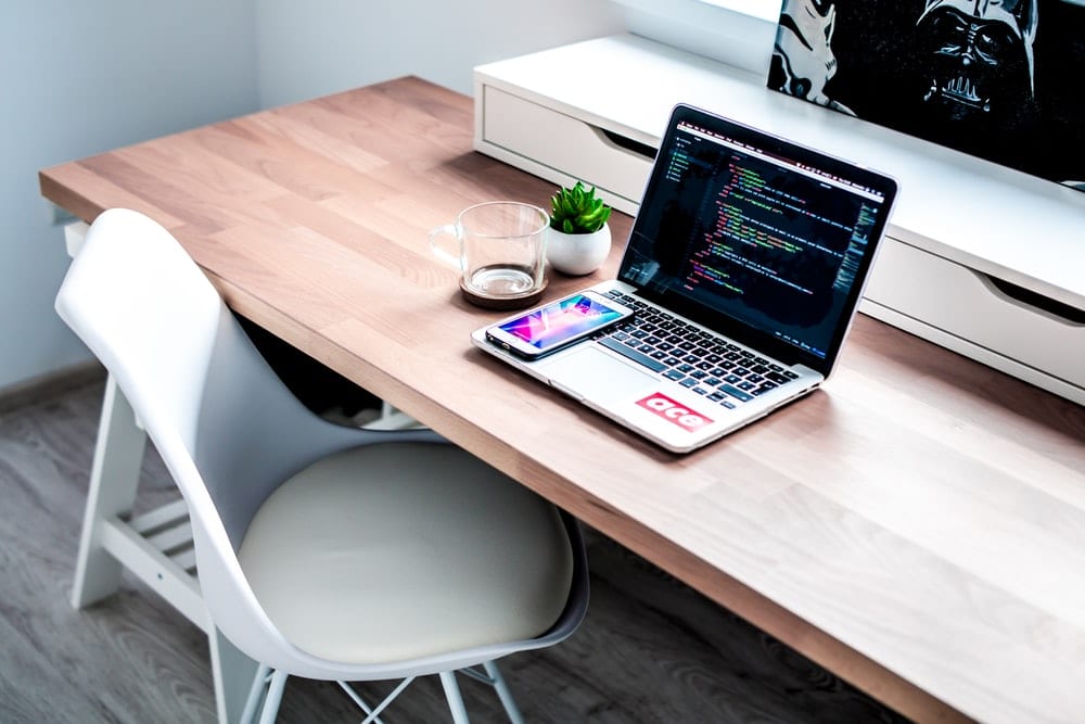  smartphone on laptop computer on top of brown wooden desk