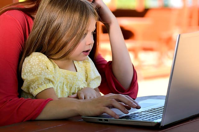 Young girl watching parent use computer