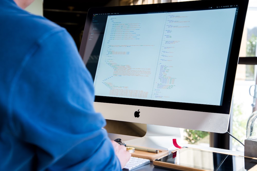 An apprentice software developer writing lines of code on a computer
