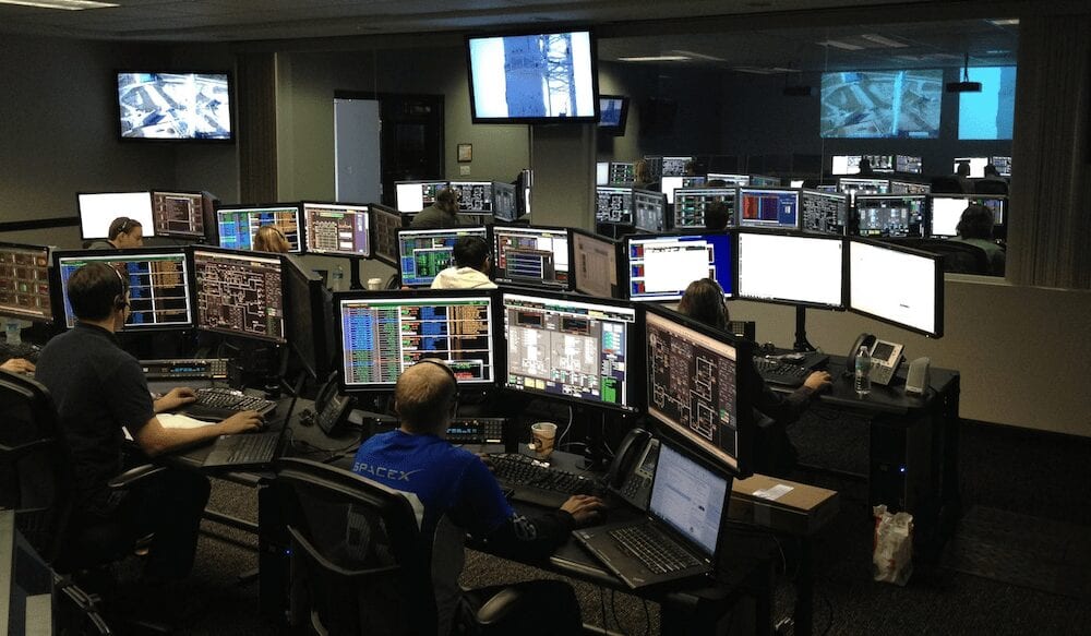 A room full of qualified computer science professionals working on multiple monitors. 