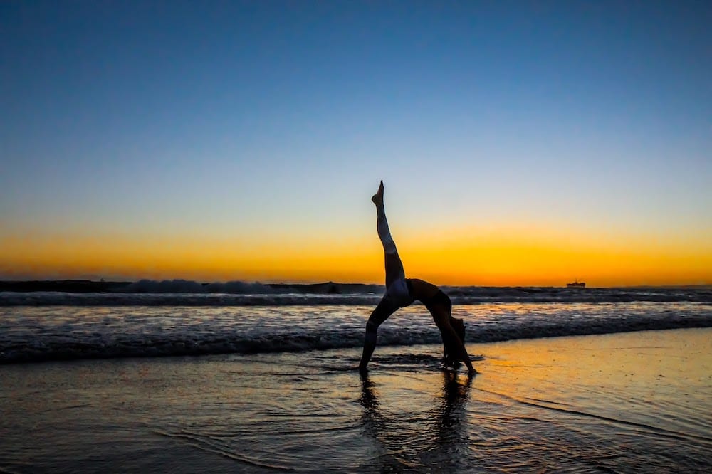 A person doing yoga on a beach.