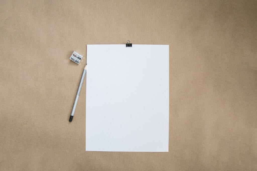 A stark, blank page with a pencil and pencil sharpener on a table.