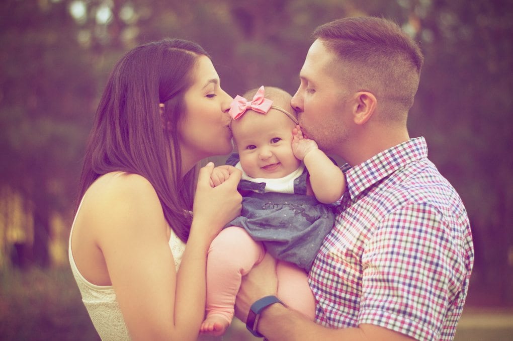 Parents kissing a baby