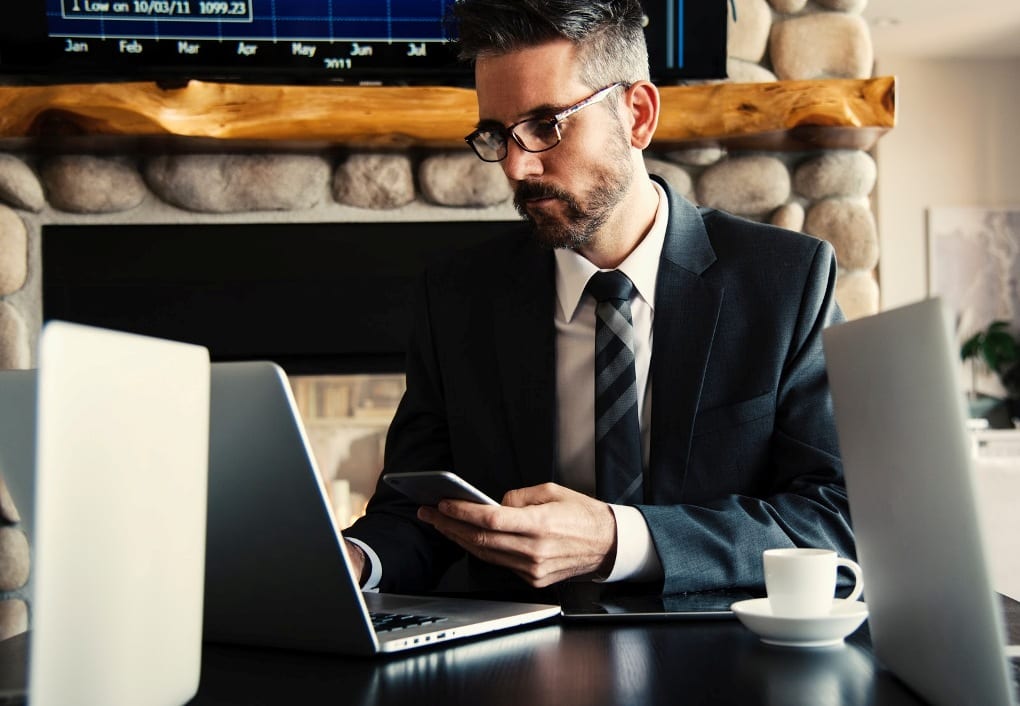 A person working on computer and phone simultaneously