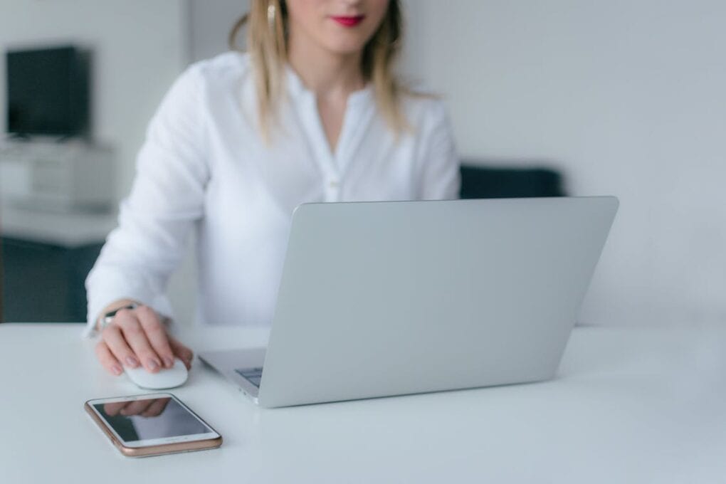 A person works on a laptop next to a mobile phone