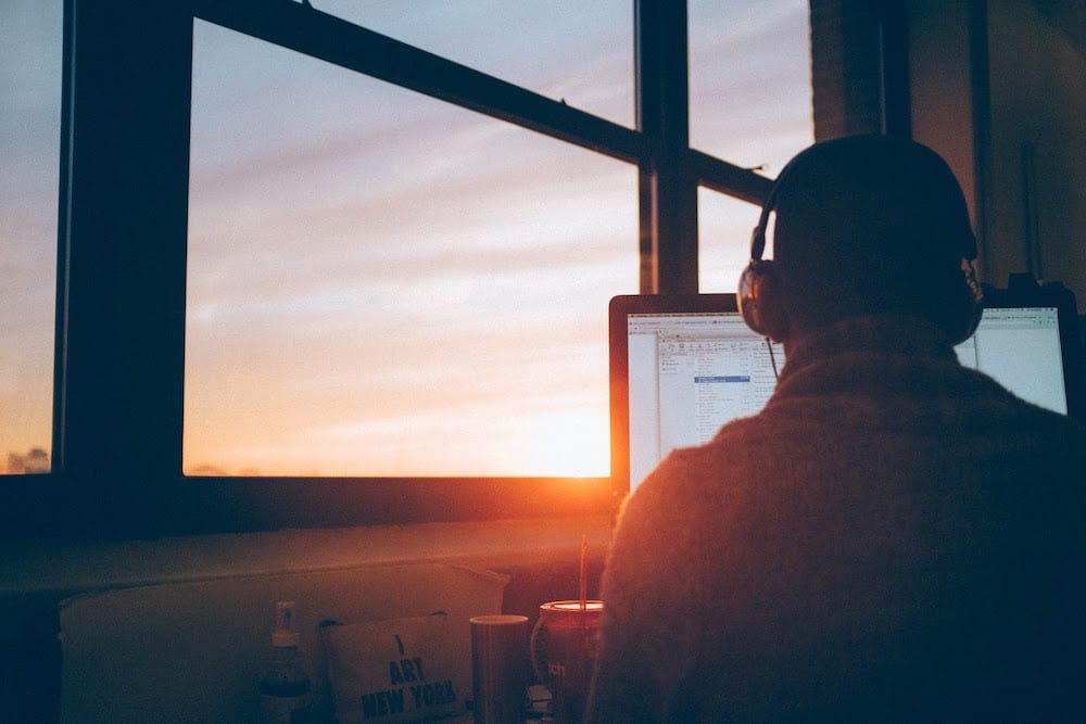 A student using a computer to search for internships for computer science students at sunset.