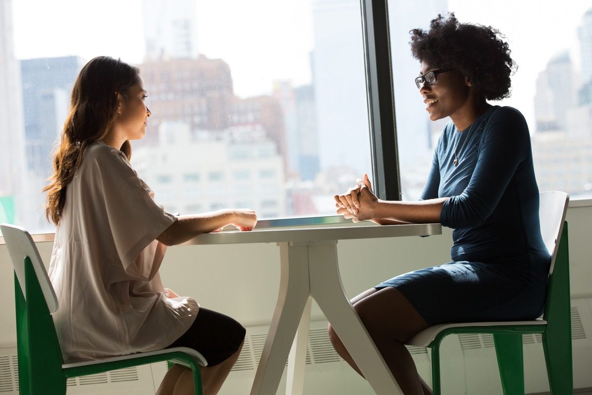 Two individuals sitting at a table practicing behavioral interview questions.