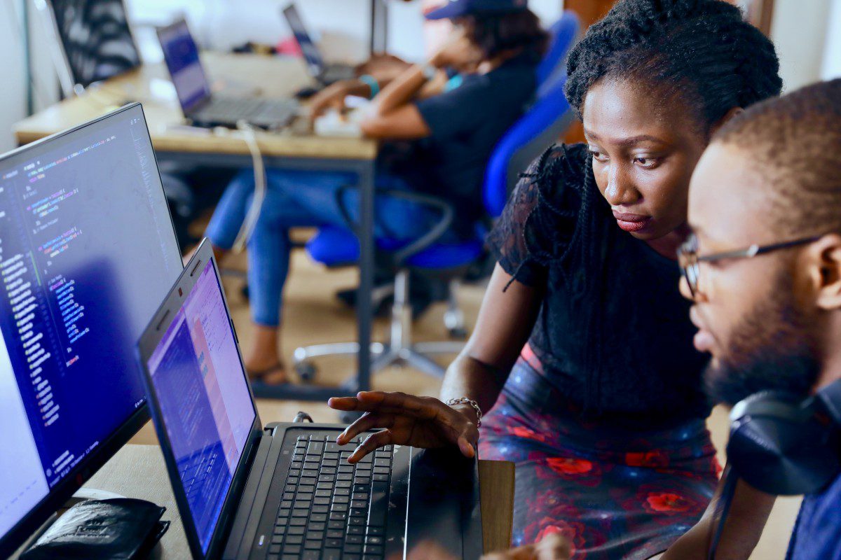 Two programming professionals working on a complex coding problem on a computer.