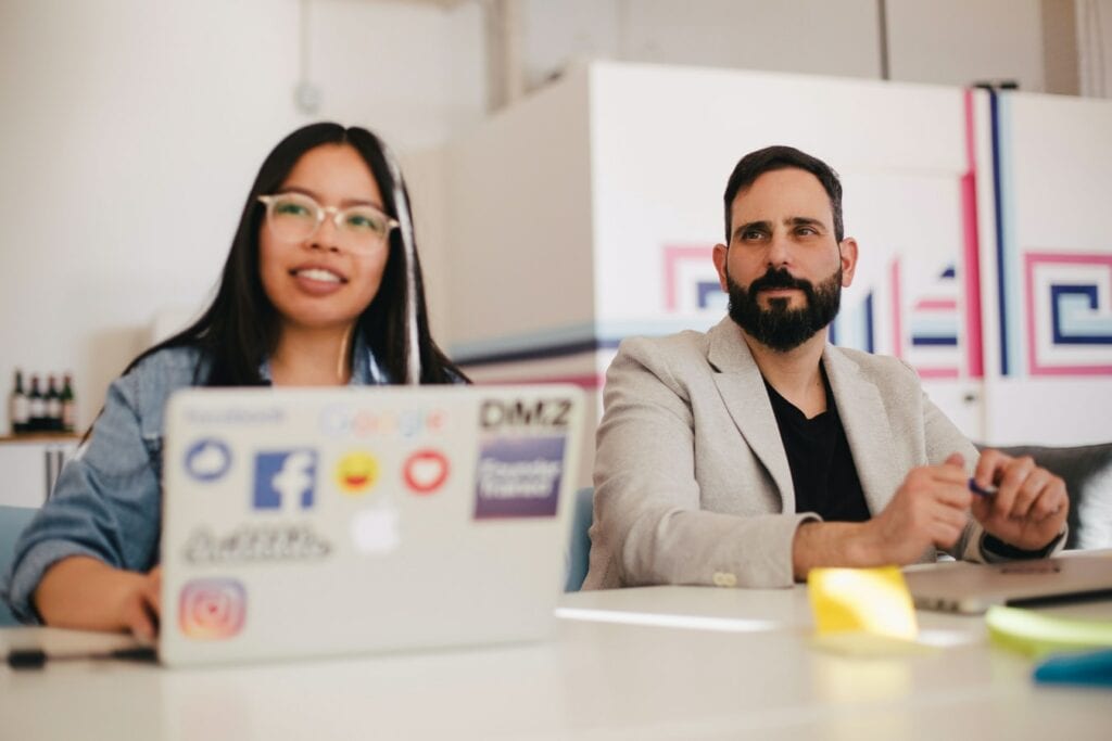 A woman on her laptop sits beside a man.