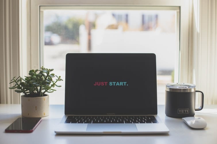 a laptop displaying "just start."