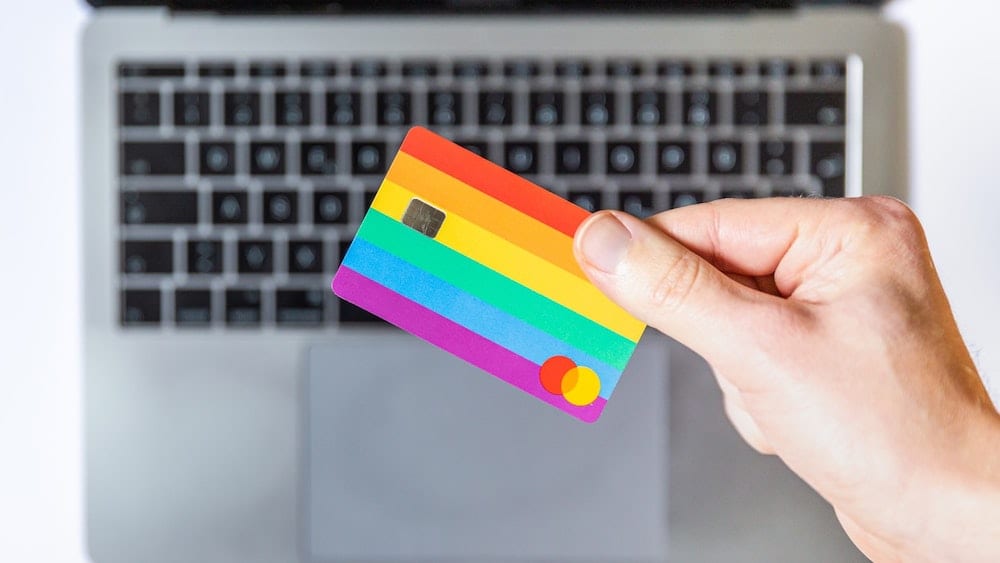 A hand holding a card above the keyboard of a laptop