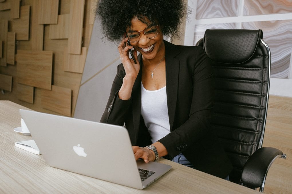 A person smiling and using a laptop during a business call. 