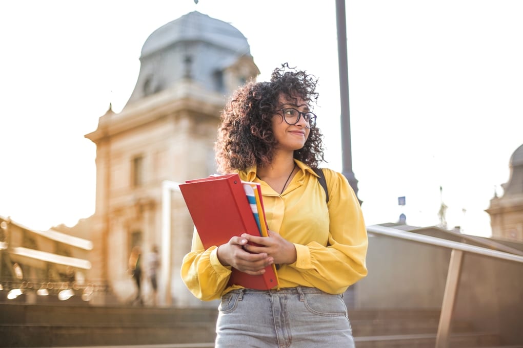 Woman in Yellow holding books
