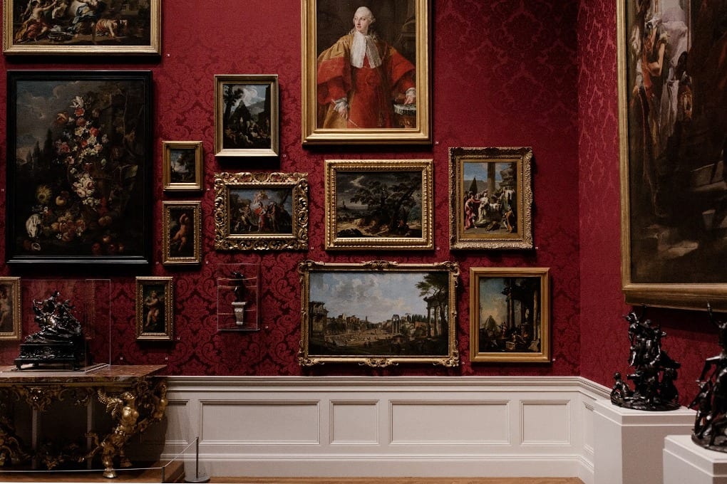 A museum with a variety of portraits on the wall. 