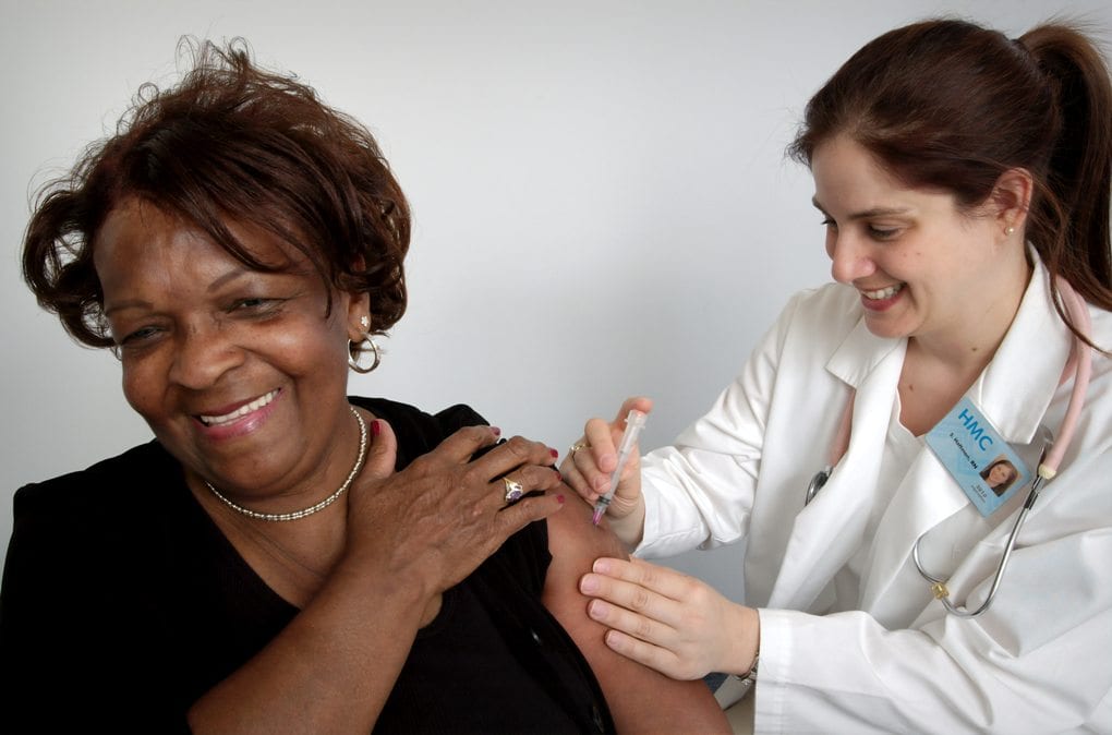 A registered nurse is administering a vaccine to a lady.
